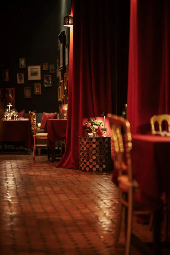 Comedor de Le Petit LØV con cortinas rojas y luz cálida